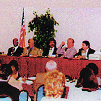 Shawn Rae seated on a conference panel with an audience in the foreground